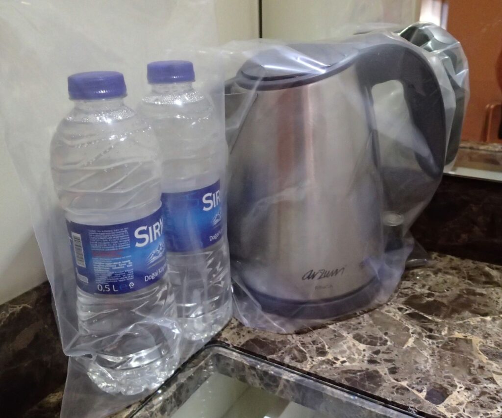 Plastic wrapped water bottles and kettle in hotel Turkey