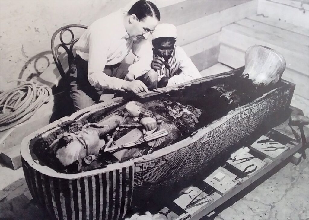 Howard Carter and Egyptian man inspecting King Tutankhamun's mummy, The Boy King