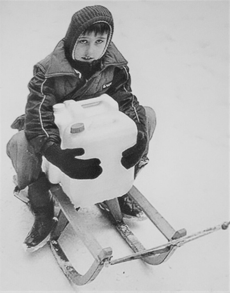 Child with sleigh and water containers